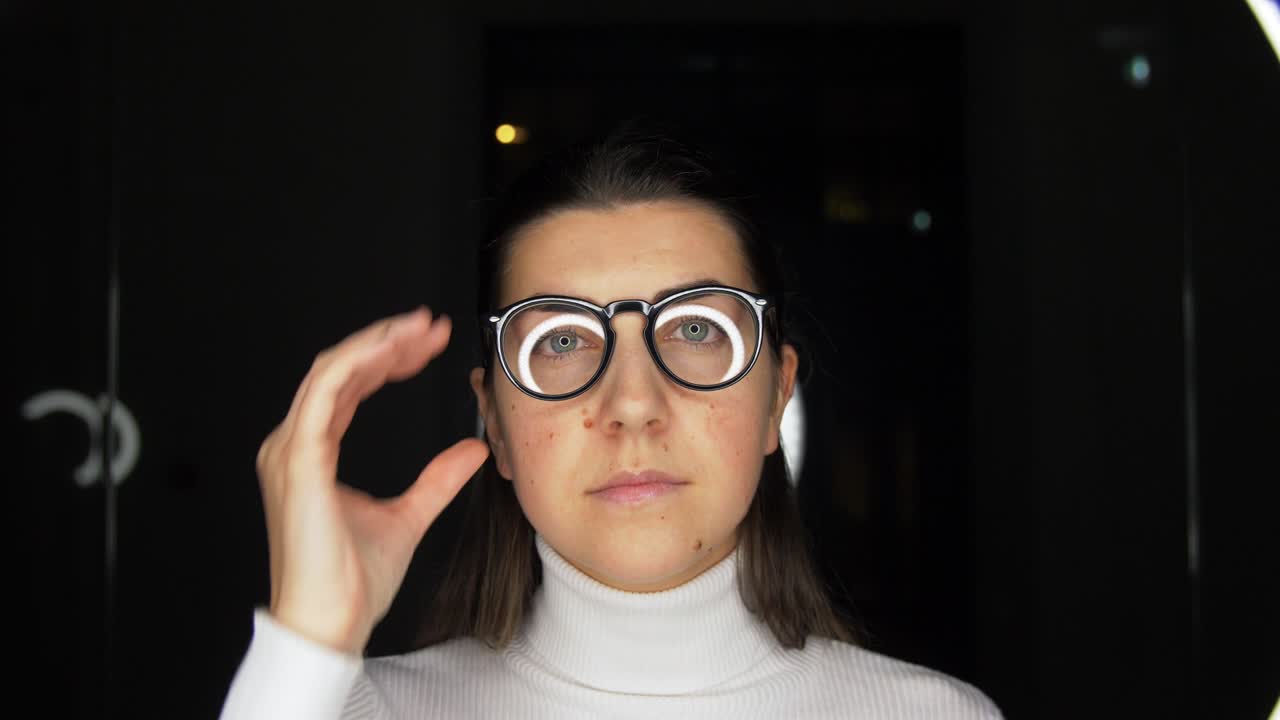 mujer con gafas sobre iluminación blanca en negro