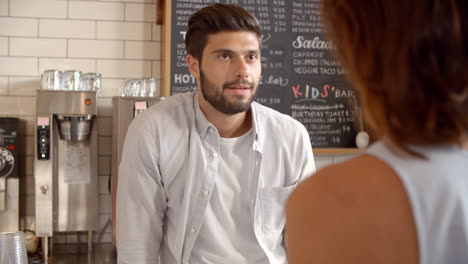 barista taking card payment from a customer at a coffee shop