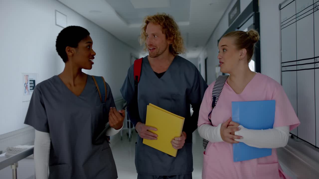 Happy diverse doctors talking and walking in corridor at hospital, slow motion