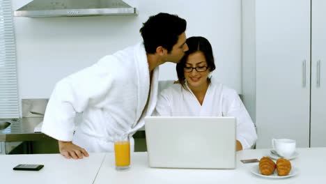 Man-kissing-his-girlfriend-while-she-is-taking-her-breakfast