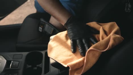 Close-up-of-a-male-wearing-black-gloves-cleaning-a-white-car-with-black-interior-with-a-microfiber-cloth-in-slow-motion