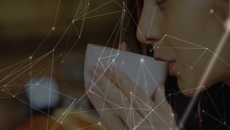 woman lifting white ceramic cup in café scene, showcasing glowing tech network overlay