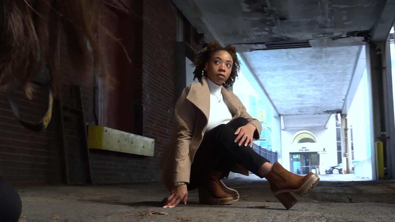 чернокожая модель позирует фотографу в переулке