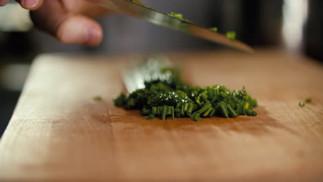 male hand cutting chives, then cleans the knive with fingers