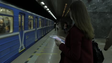 mujer usando una tableta en una estación de metro