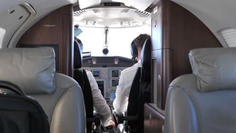 back view of pilot and co-pilot in the cockpit of a private jet plane