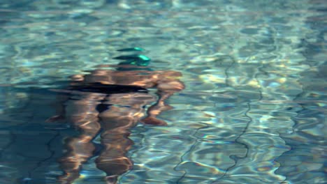 muscular swimmer swimming underwater in the pool