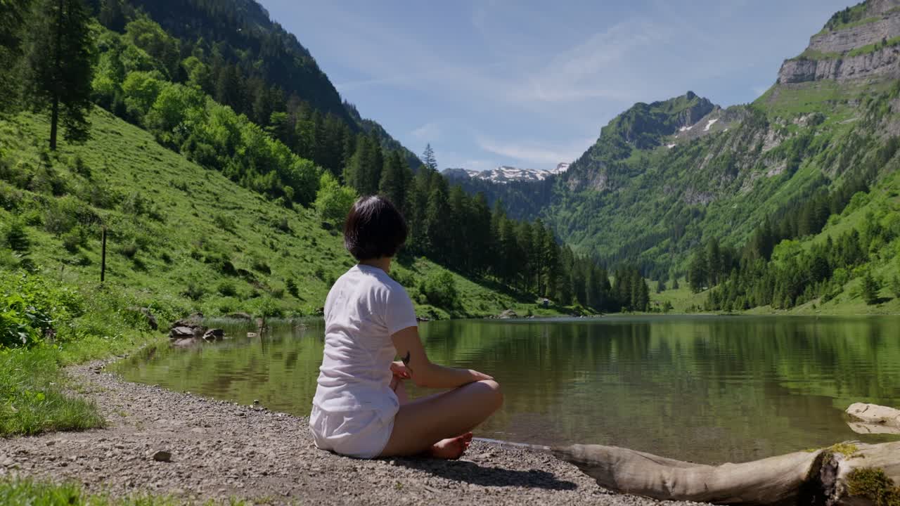 Woman sitting on Rocky shore of natural during sunny day in Switzerland. Beautiful mountain view in summer. Relaxing in magnificent landscape. Close up.