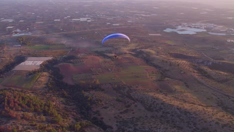 Paraglider-above-rural-Italy-during-sunset,-aerial