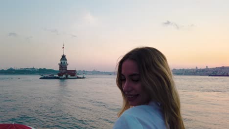 slow motion:beautiful girl enjoys sunset view of bosphorus with view of maiden tower at background in istanbul