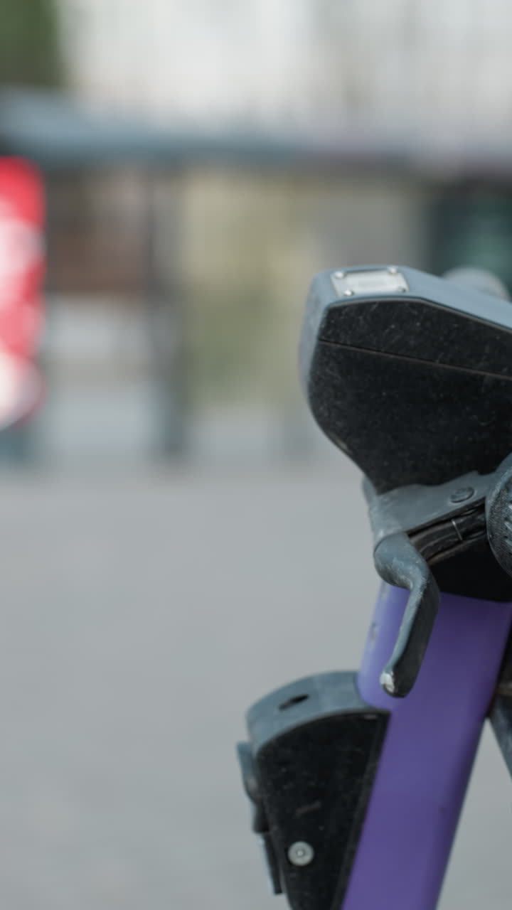 vista cercana de scooters eléctricos púrpuras estacionados en un área ocupada de la ciudad, el fondo incluye el paisaje urbano borroso con coches en movimiento y personas