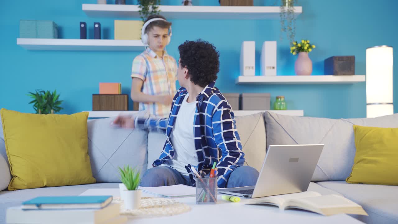 The naughty boy bothers his older brother, who is studying.