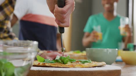 Happy-diverse-male-teenage-friends-preparing-pizza-in-kitchen,-slow-motion