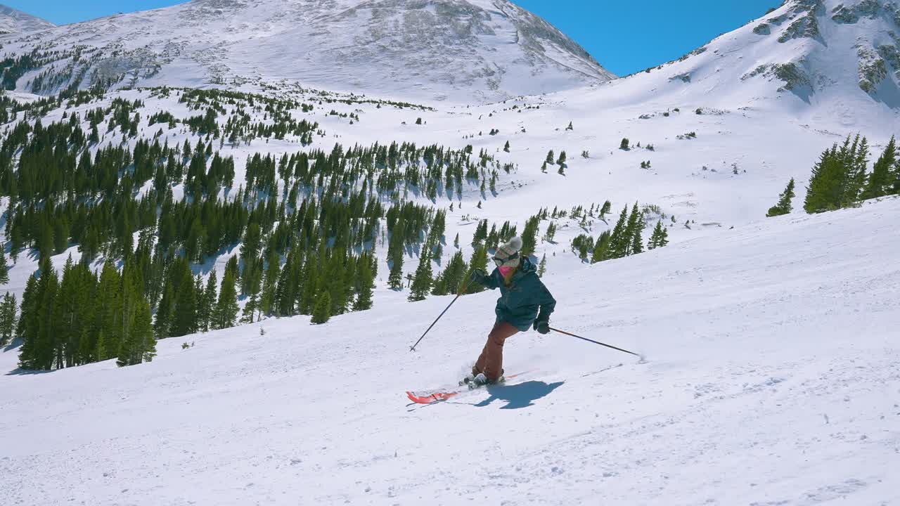 катание на лыжах вниз по крутой горе в медленном движении с живописными снежными горными вершинами на расстоянии