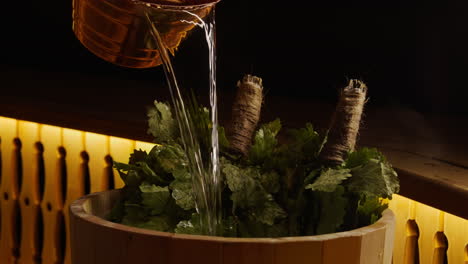 pouring water over branches in a sauna