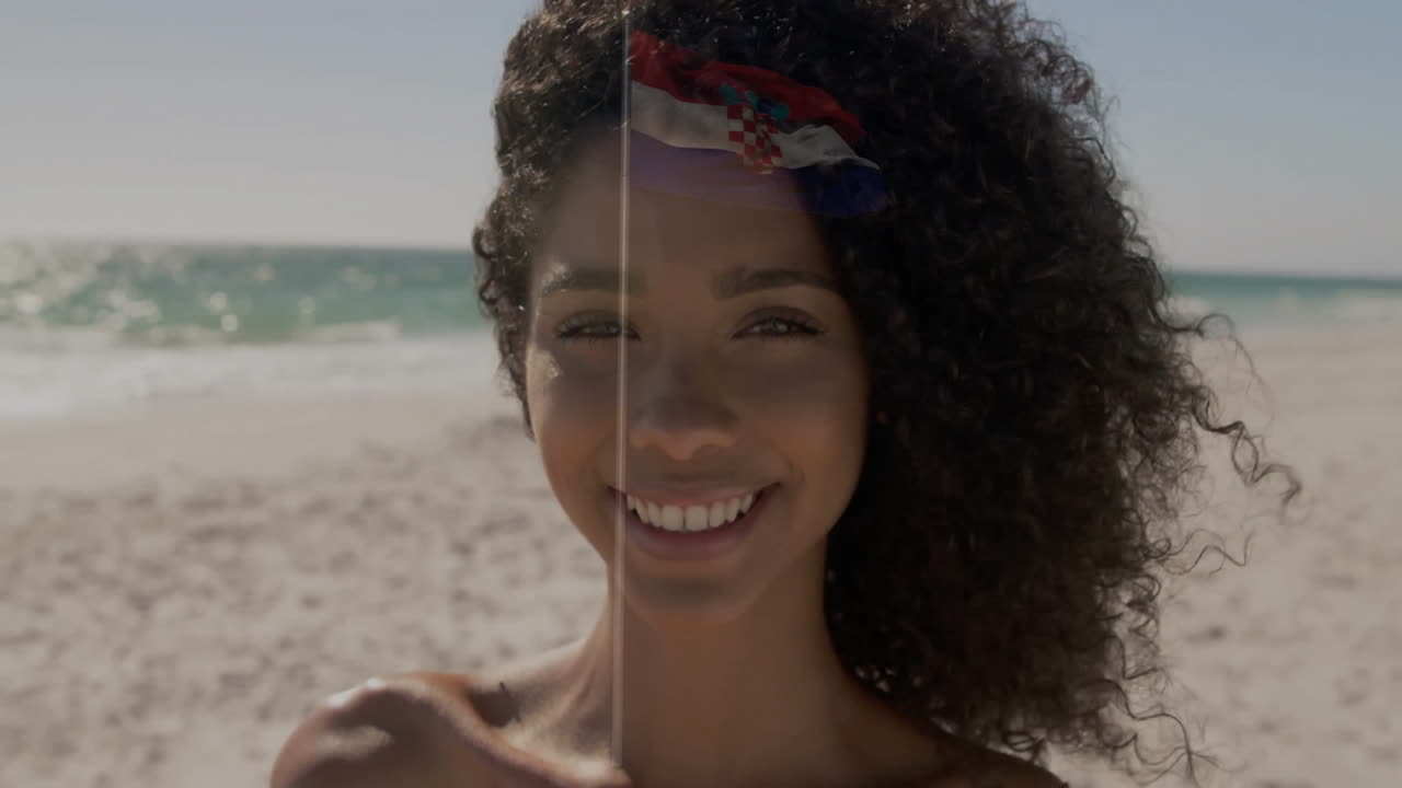 On sunny beach, woman with curly hair wearing headband, smiling brightly