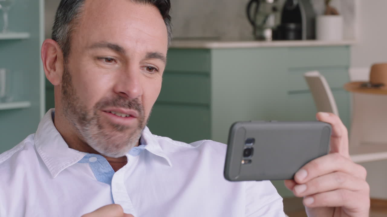 joven atractivo teniendo video chat usando smartphone disfrutando de charlar con un amigo en línea compartiendo estilo de vida relajándose en casa