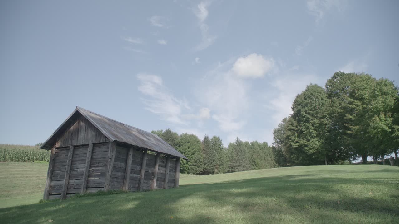 un pequeño granero de madera sobre un exuberante campo verde