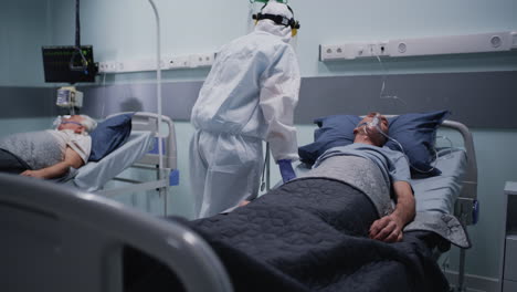 medical professional in ppe attending to patients in a hospital ward