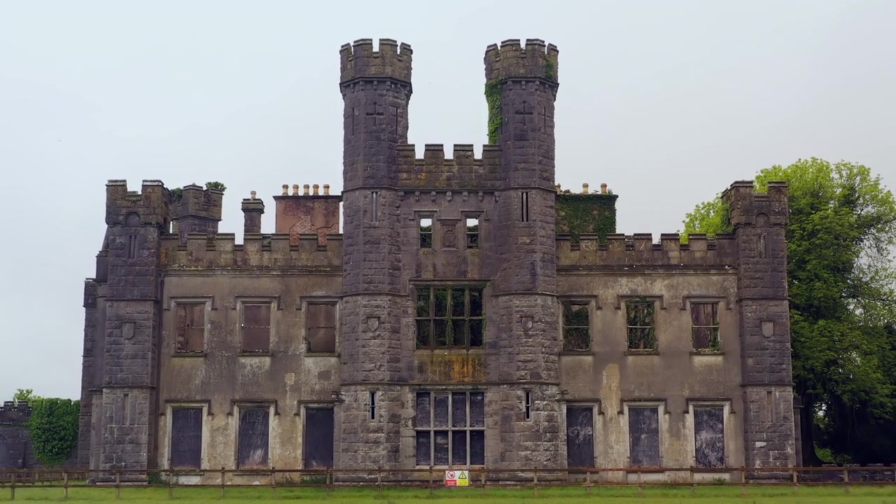 Luftaufnahme: Dolly-Zoom von markanten Zwillingstürmen bis auf Bodenniveau, gleitend über die Schlossgärten, Castle Saunderson Cavan Irland