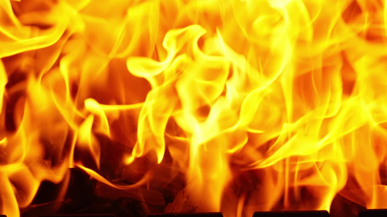 Burning flames rising from glowing coals, close-up with intense heat and energy