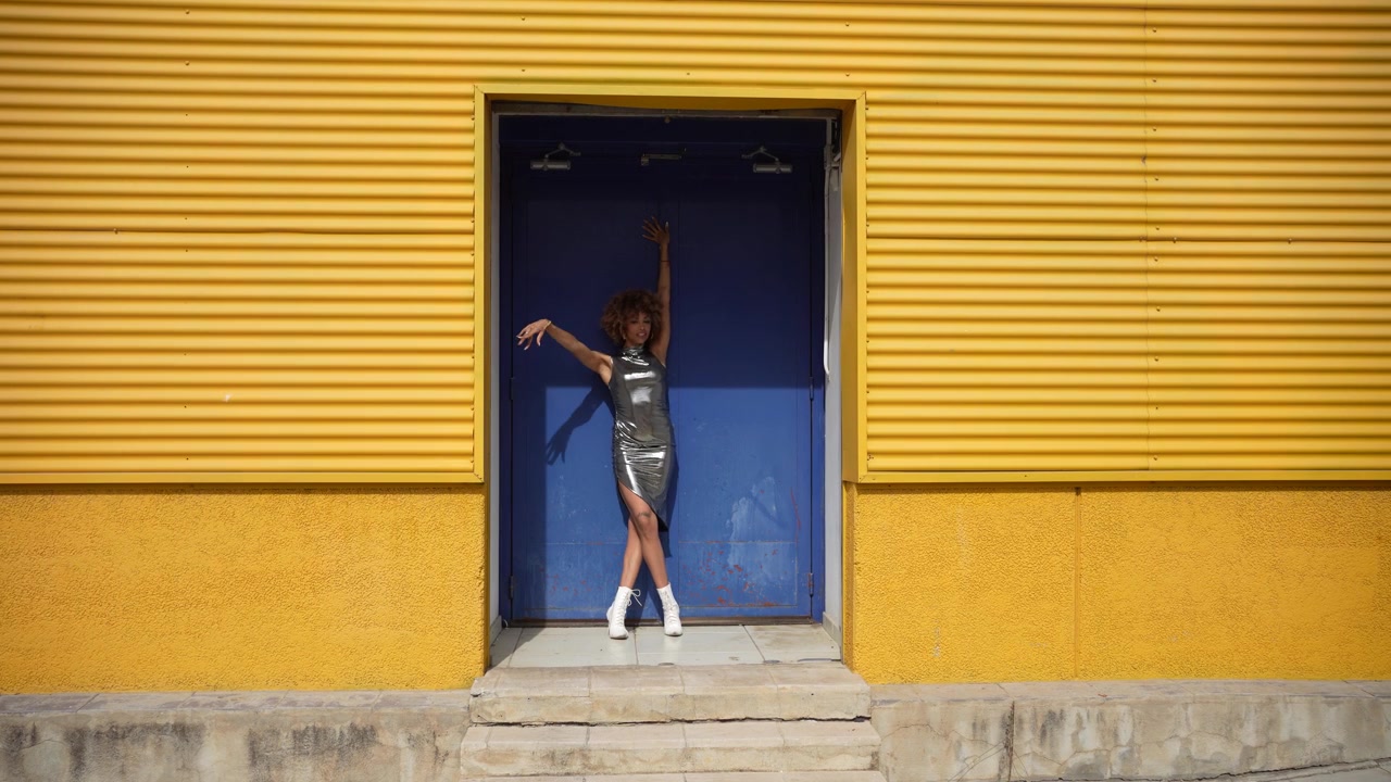 Una mujer a la moda posando con estilo frente a una pared amarilla brillante y alegre.