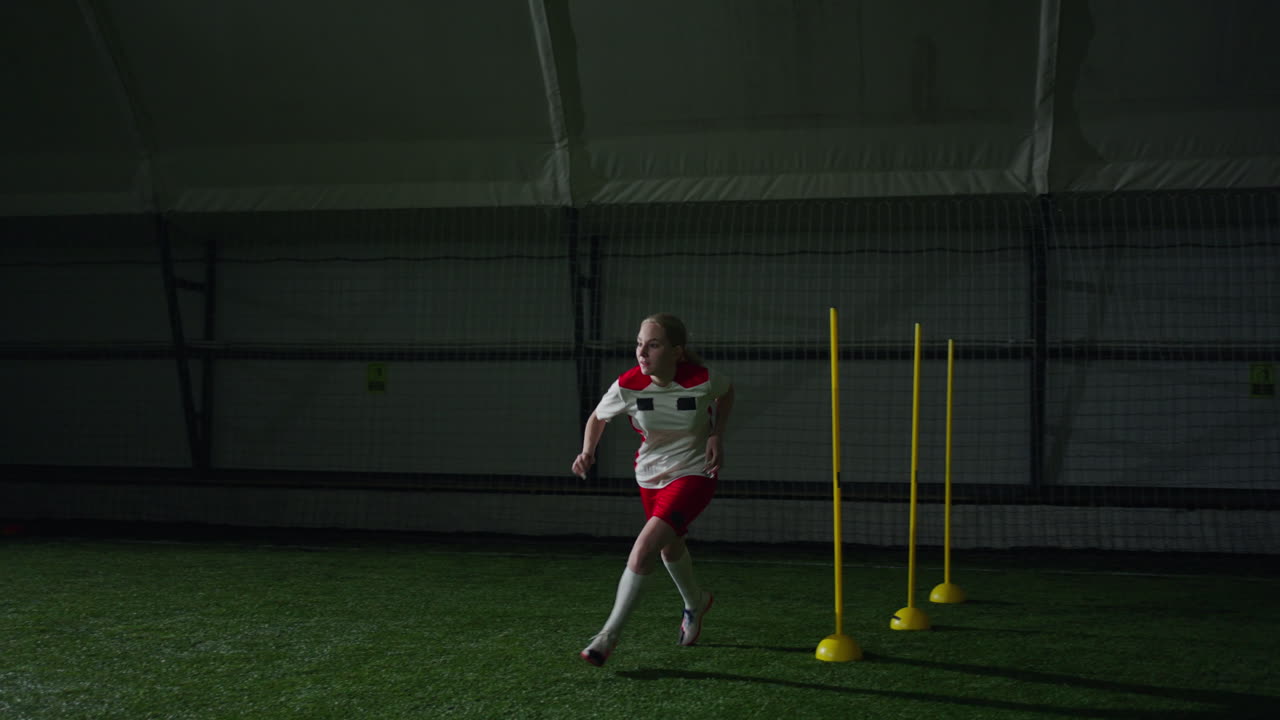 jugadora de fútbol femenina entrenando en una instalación de fútbol cubierta