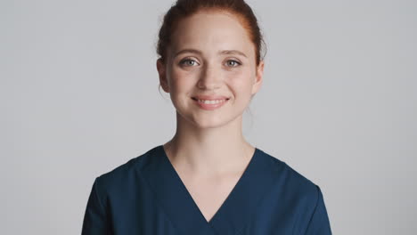 redheaded nurse in front of camera on gray background.