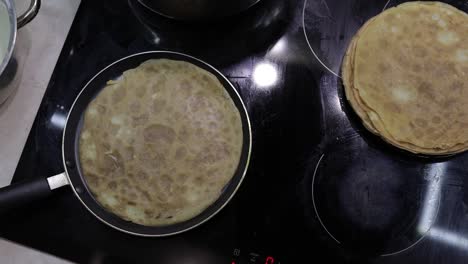 The-process-of-cooking-homemade-pancakes.-Woman-turns-pancake-in-a-frying-pan