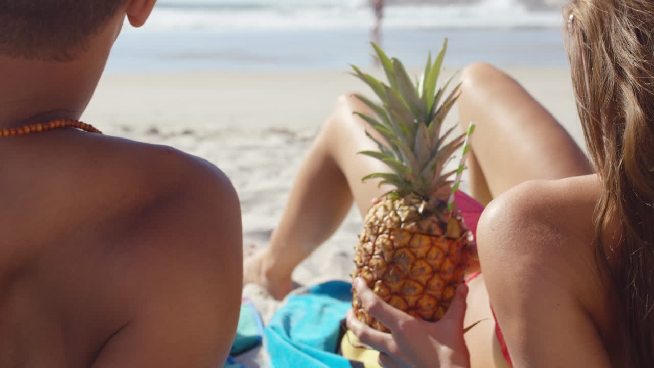 pareja multi-racial bebiendo cócteles de piña en la playa