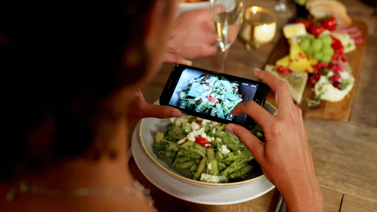 mujer tomando una foto de la comida en la mesa de la cena en el restaurante 4k 4k
