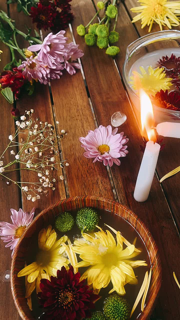 Blomsterarrangement med stearinlys og krystaller på et træbord
