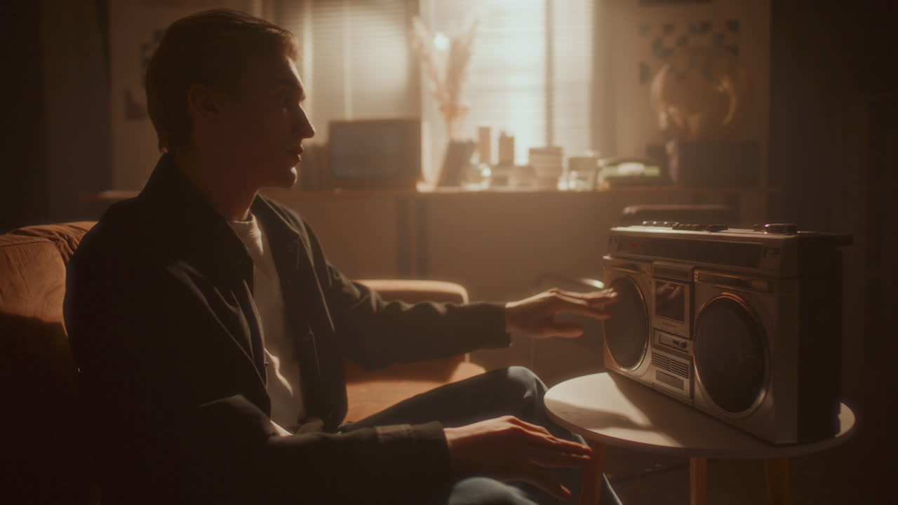 Young Relaxed Man Listening to Music on Retro Boombox in Cozy Room