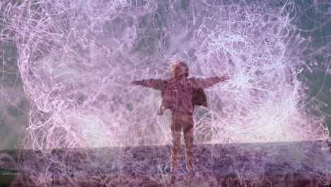 Standing with arms outstretched, person surrounded by swirling animation light patterns