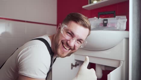 plumber in working uniform and goggles showing thumbs up