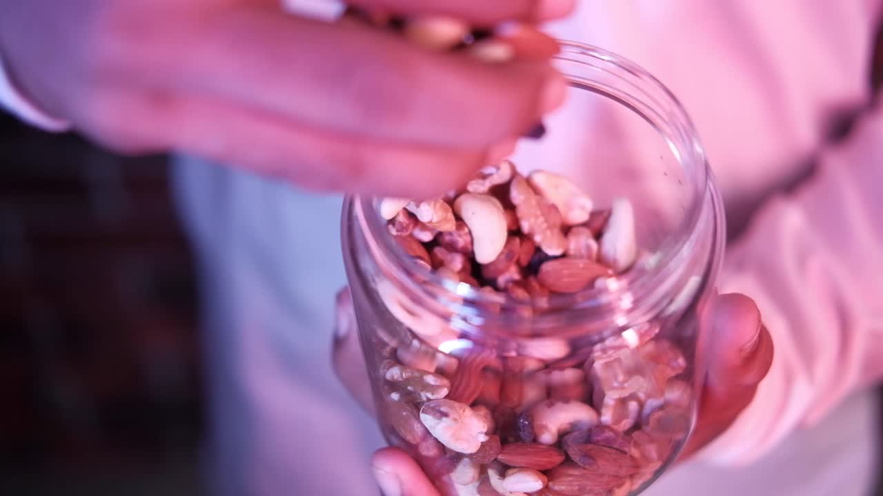 혼합 된 견과류 의 항아리 를 들고 있는 사람