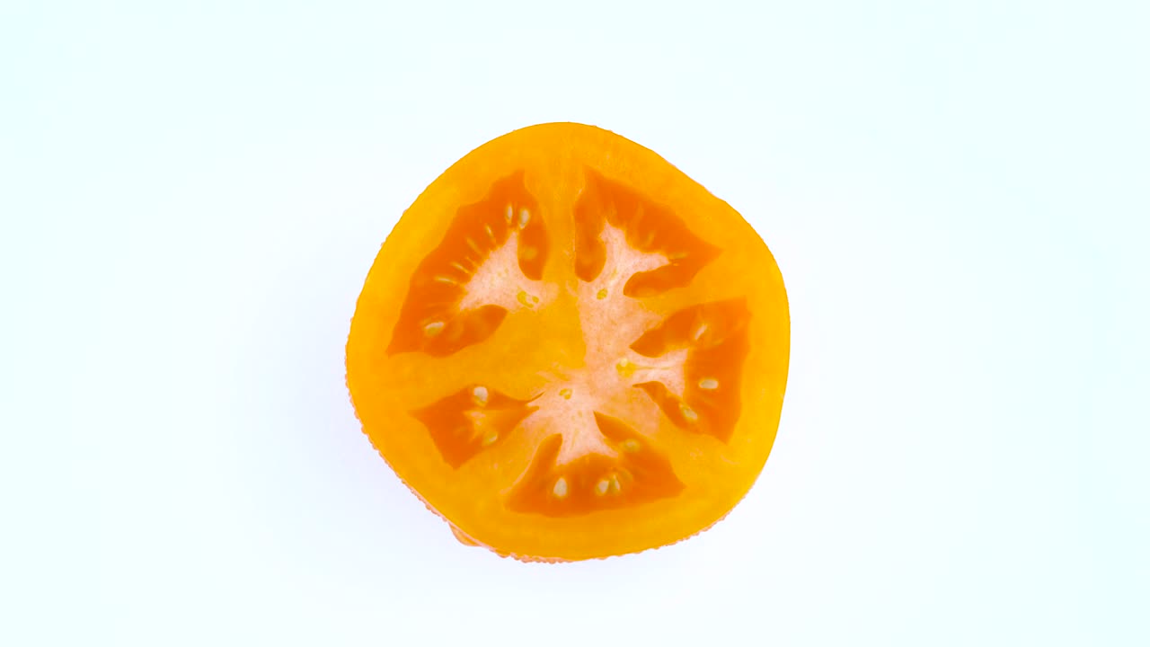 위쪽에서 볼 때 오렌지색 토마토의 절반이 물방울로 여 있고, 색 배경에 고립된 턴테이블을 회전시니다.