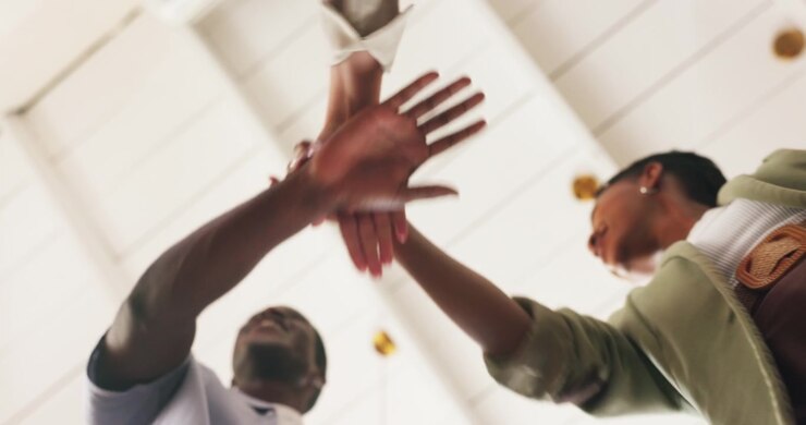 Diverse Team Joining Hands in Unity and Celebrating Success