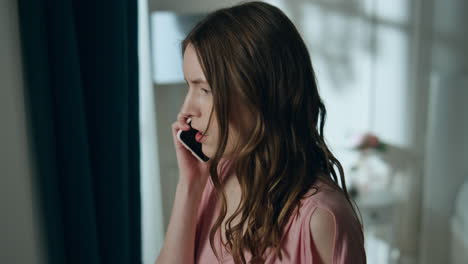 una chica enojada discute por teléfono móvil en una ventana de casa. grito femenino estresado