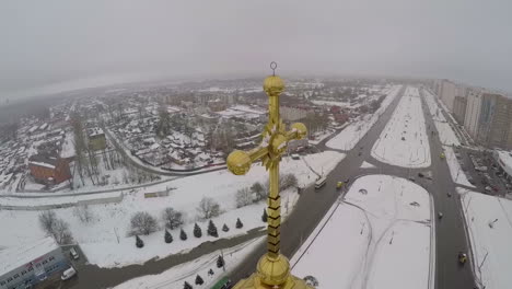 golden cross on the church in city aerial view