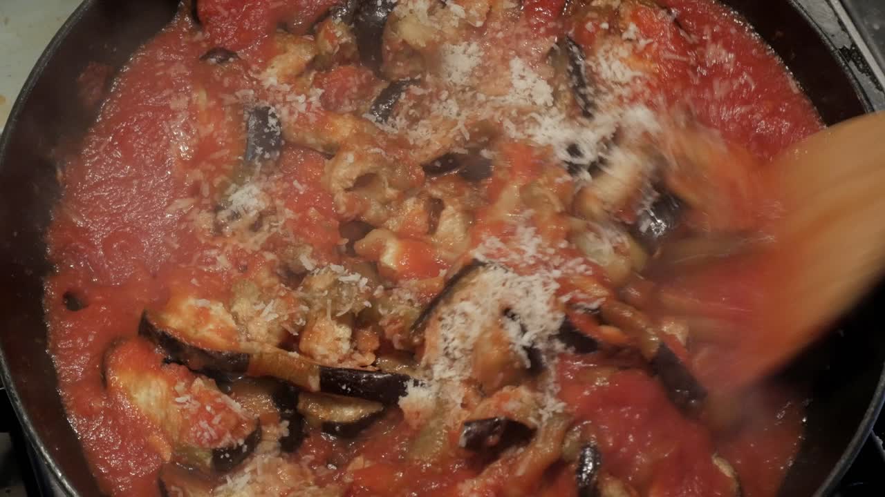 Cottura di salsa di melanzane in una pentola con formaggio grattugiato sopra