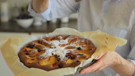 Nahaufnahme-Einer-älteren-Frau,-Die-Frisch-Gebackene-Torte-Mit-Puderzucker-Bestreut