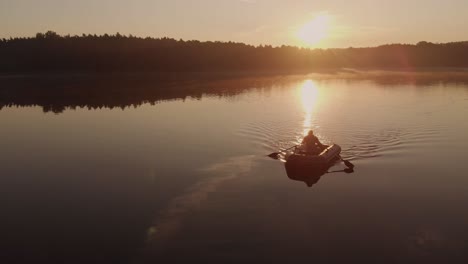 Joven-Remando-En-Un-Bote-Inflable-En-El-Lago-Sereno-En-Una-Puesta-De-Sol-Cerca-Del-Pueblo-De-Rogowko,-Polonia