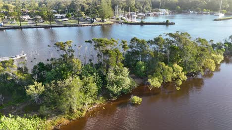 Aerial footage captures a boat navigating a scenic river surrounded by lush greenery under clear skies