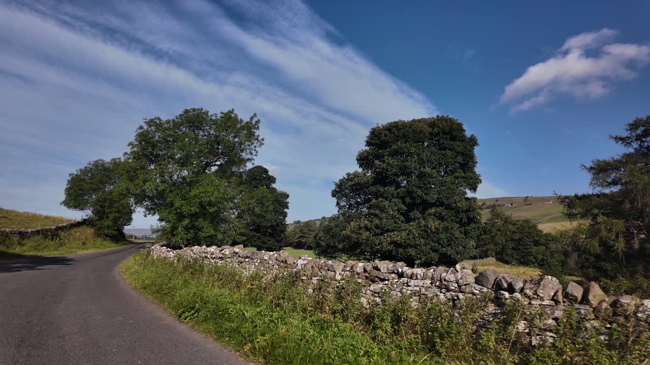 Quiet country lane in Weardale, County Durham on a sunny morning with stone walls and trees