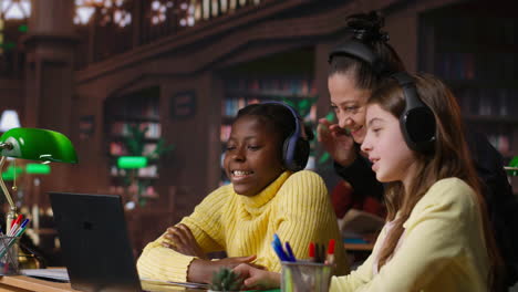 students collaborating on a laptop in a library