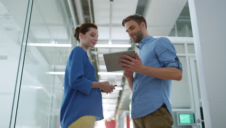 Colleagues-looking-tablet-in-modern-office.-People-discussing-business-indoors.