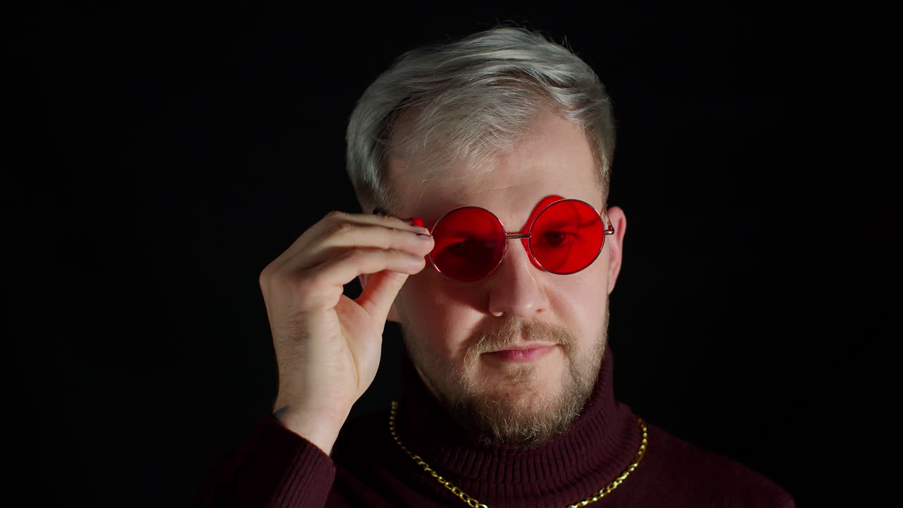 un joven seductor con gafas de sol, una sonrisa encantadora, un guiño, un parpadeo, coqueteando contra un fondo negro