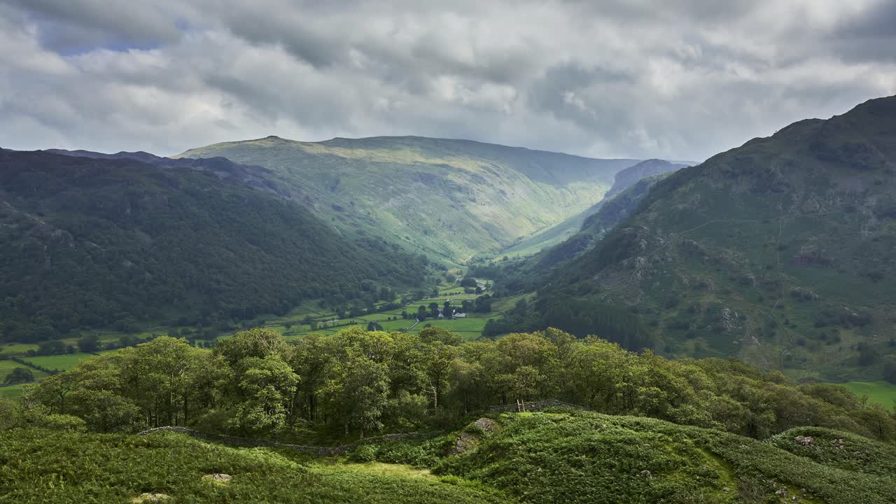 스톤스웨이트 계곡과 움직이는 태양 광선과 구름이 있는 인근 산등성이를 보여주는 영국 호수 지구에서 느린 패닝 시간 경과