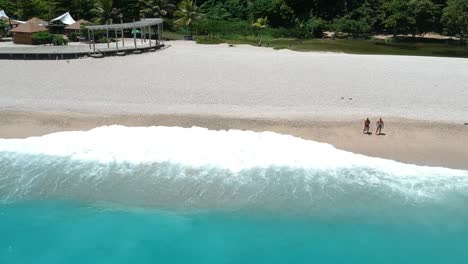 aerial view of the amazingly blue water of the caribbean crashes on the rocky beach of los patos, dominican republic as people enjoy the summer sunshine and their vacation
